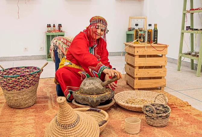 Woman in traditional dress grinding argan kernels on a stone hand mill