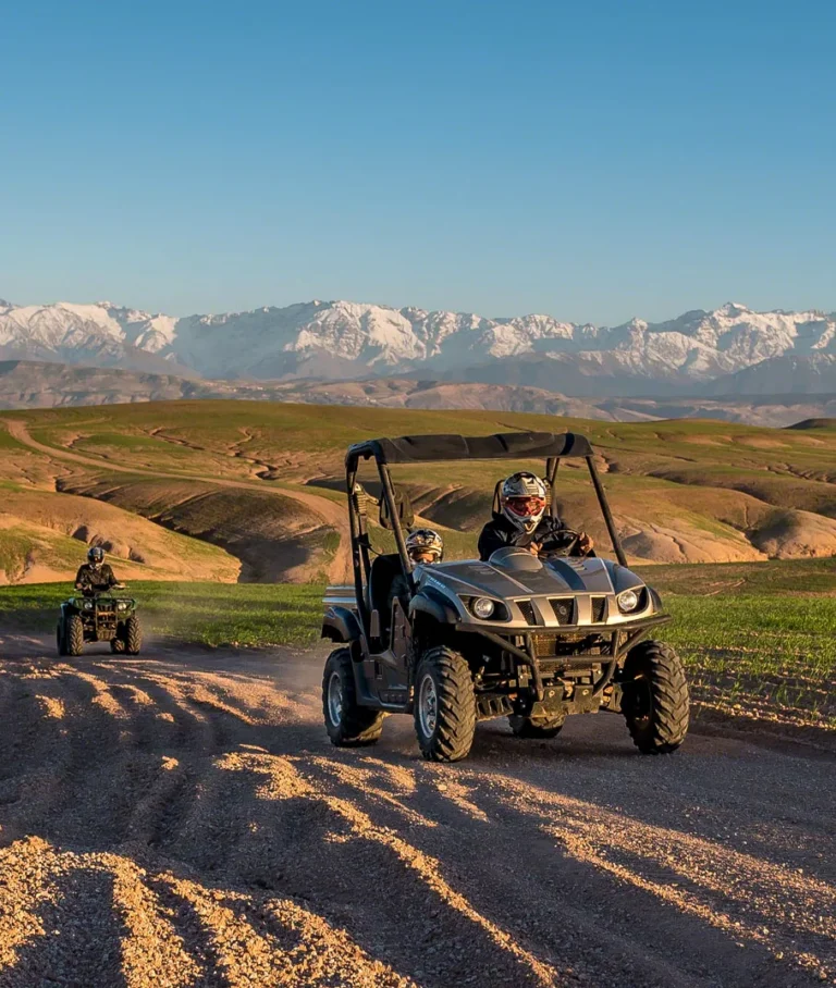 Off-road buggy on a dirt track in the Agafay hills with the snowy Atlas behind