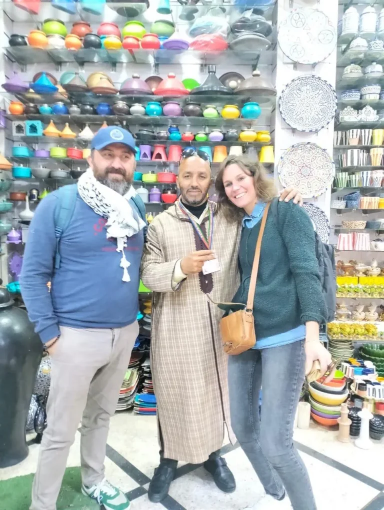 Couple and their guide in front of shelves of painted tagines