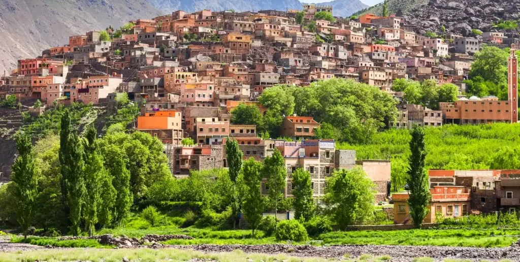 Village of earth and stone houses on a green hillside in the High Atlas