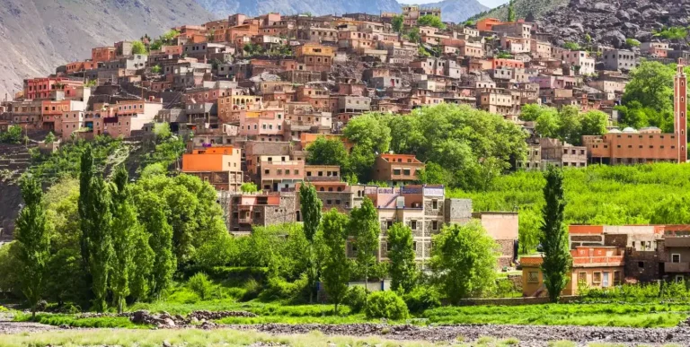 Village of earth and stone houses on a green hillside in the High Atlas