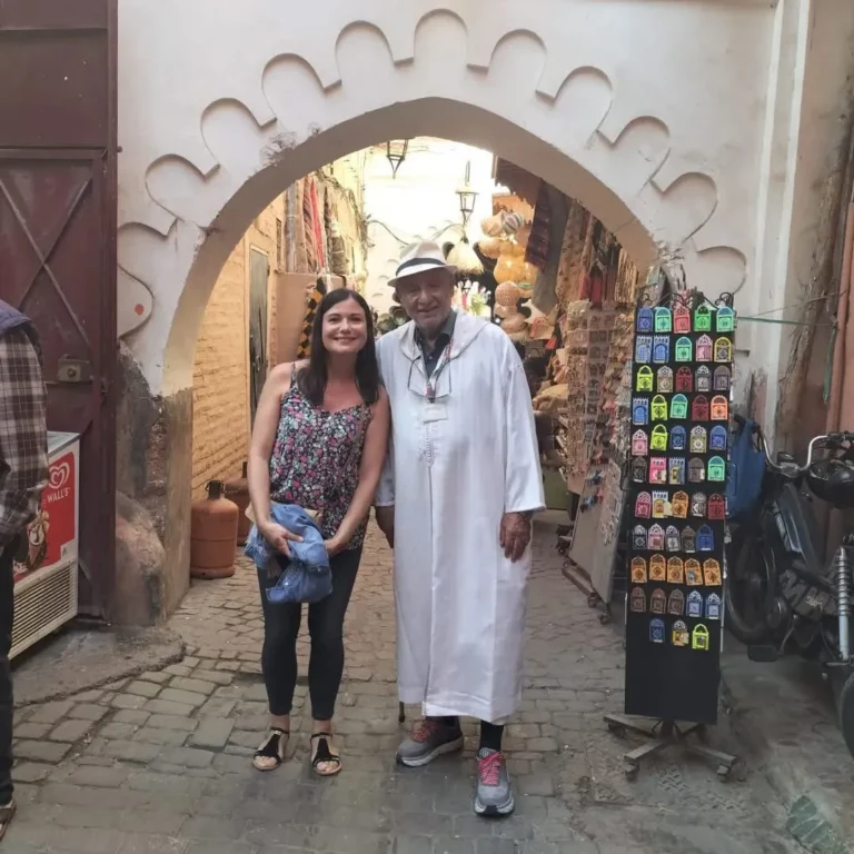 Guide in a white djellaba with a visitor under an arch in the souks