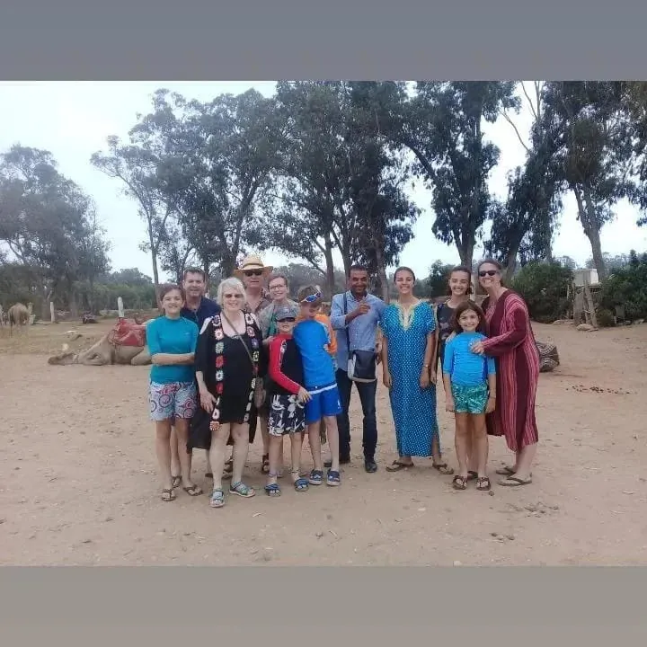 Family group in the Marrakech Palmeraie with resting camels behind them