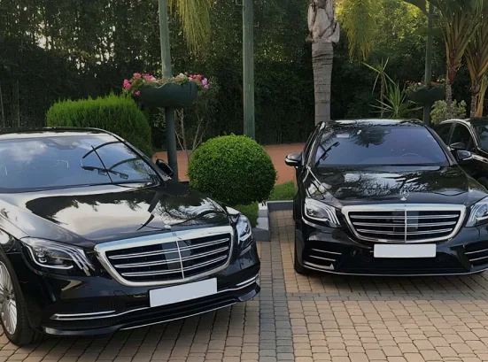 Two black saloon cars parked side by side at a hotel entrance
