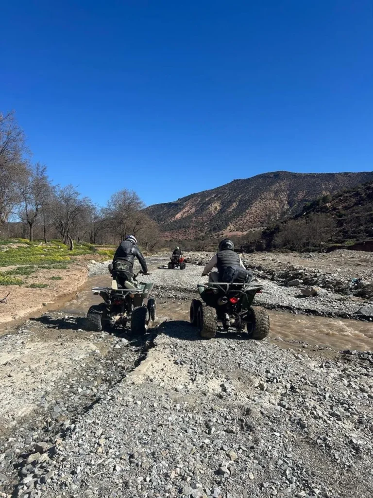 Two quad bikes crossing a dry riverbed in the Atlas foothills