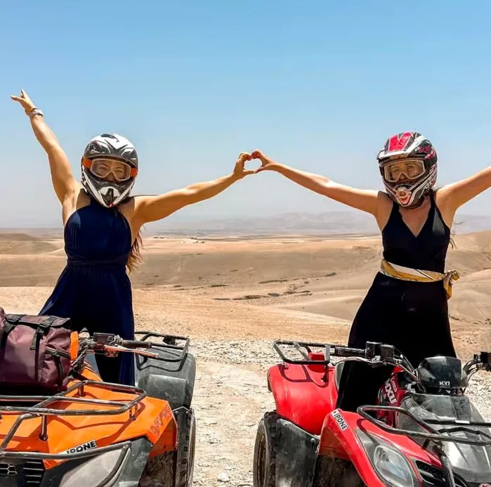 Two riders in helmets beside their quad bikes in the stony Agafay desert