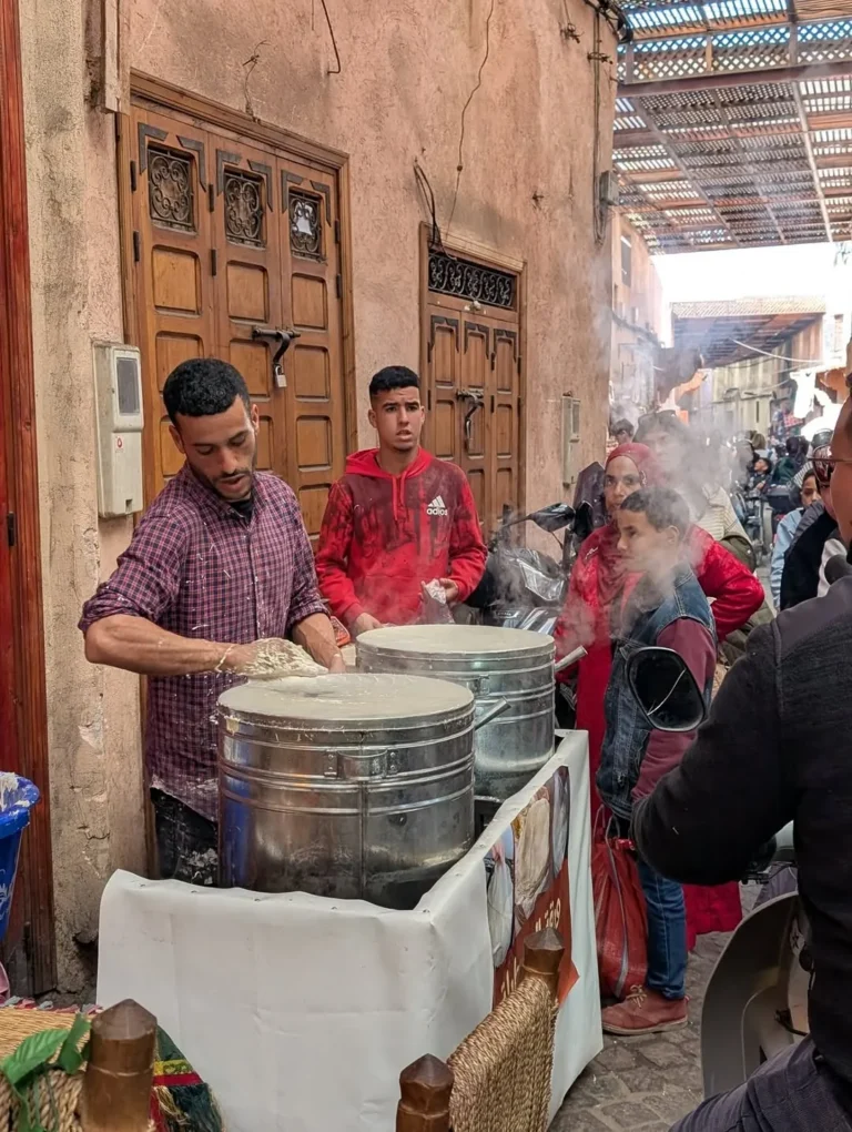 Cooks serving from steaming pots at a medina food stall